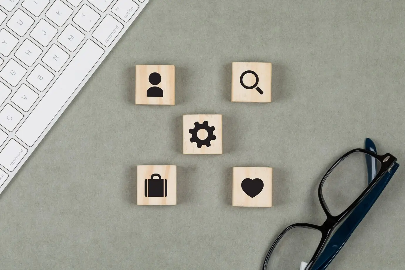 Финансовая концепция с деревянными кубиками, очками и клавиатурой на сером фоне, вид сверху.